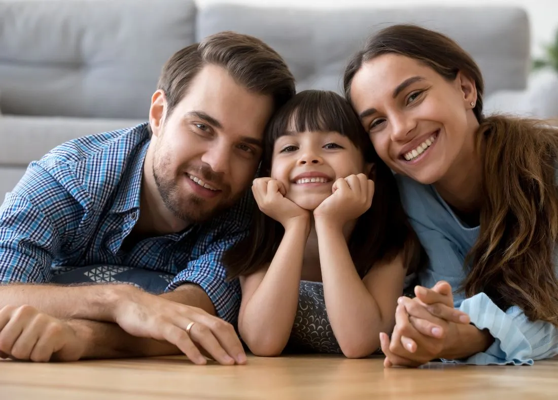 Mother, farther and young girl laid on the floor smiling