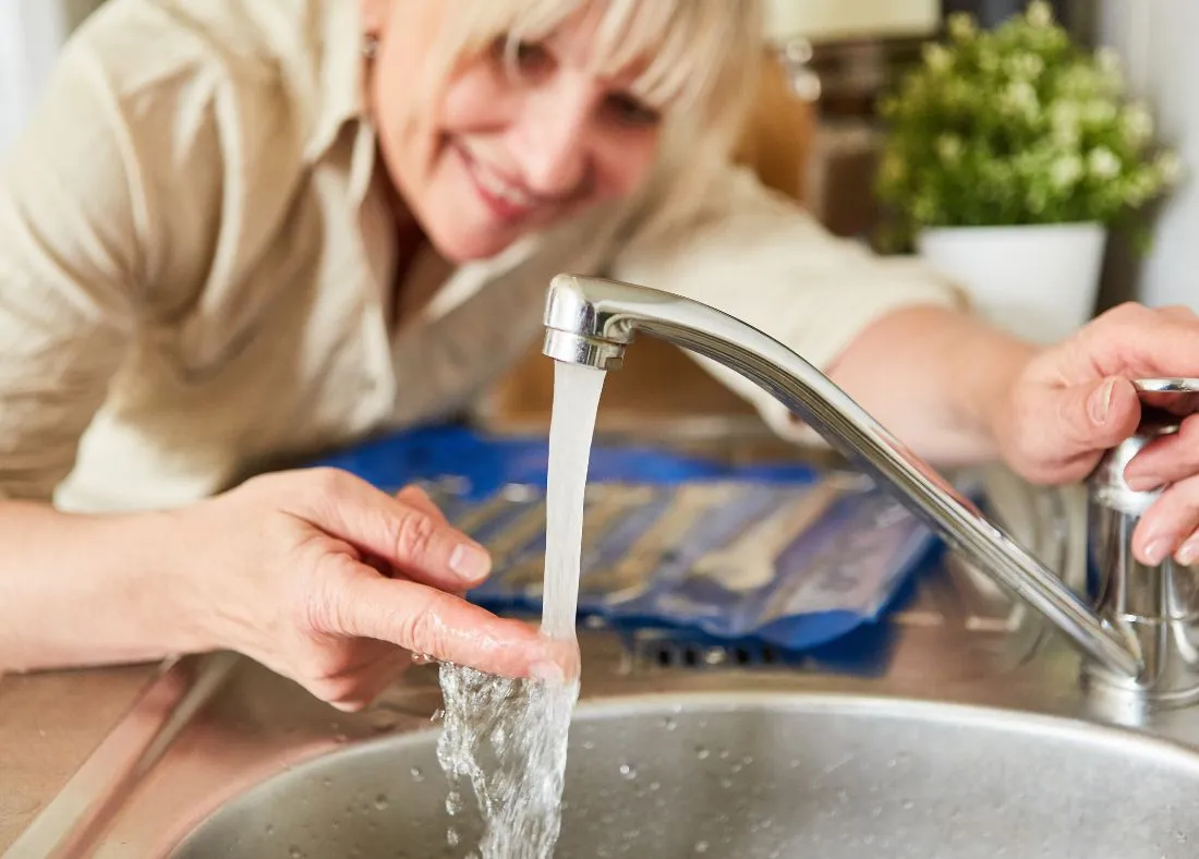 Woman checking hot water temperature